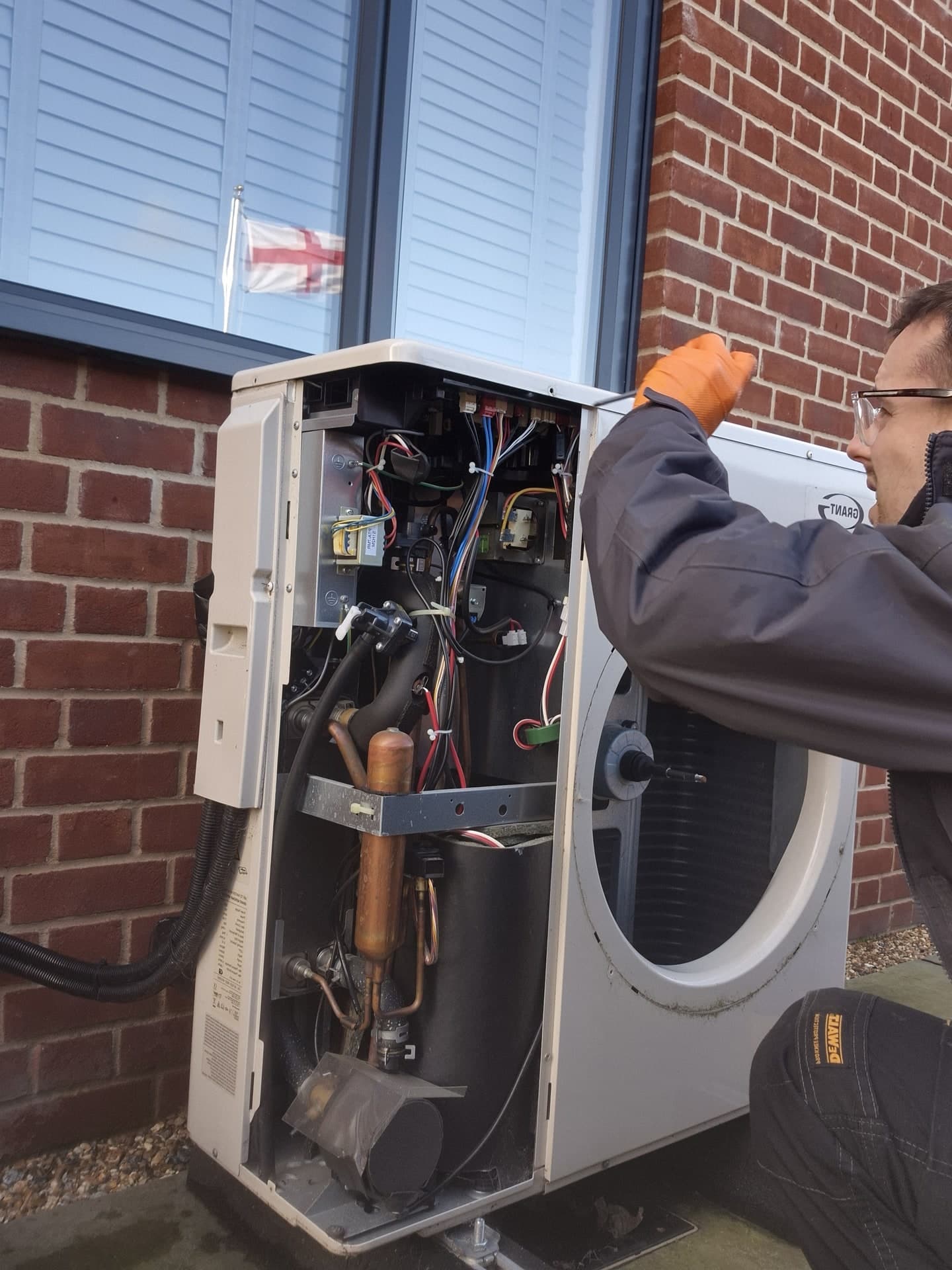 Engineer servicing an air source heat pump with the access panel removed